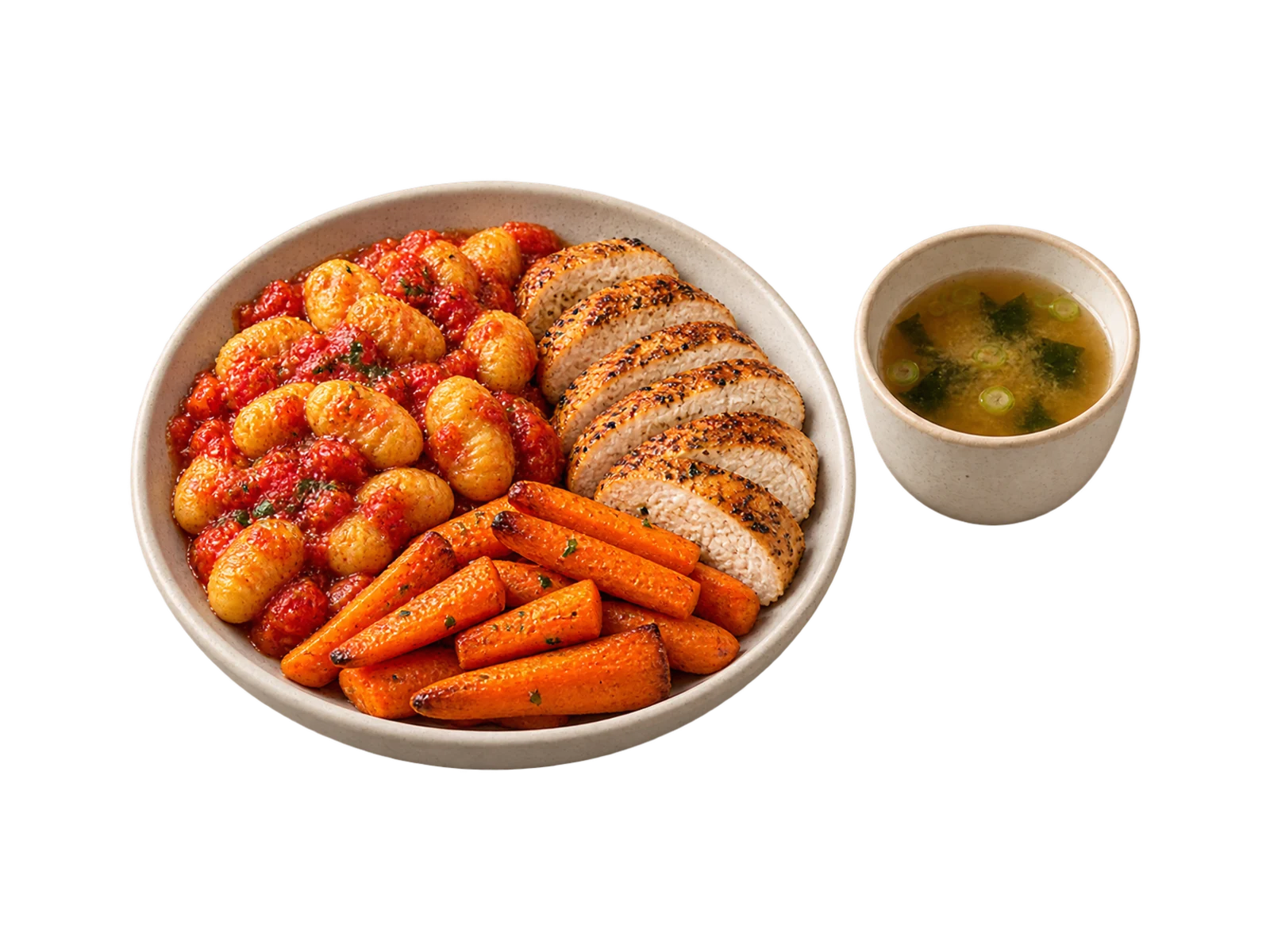 A cream plate of gnocchi in tomato sauce, sliced grilled chicken and roasted carrot batons, with a cup of miso broth.
